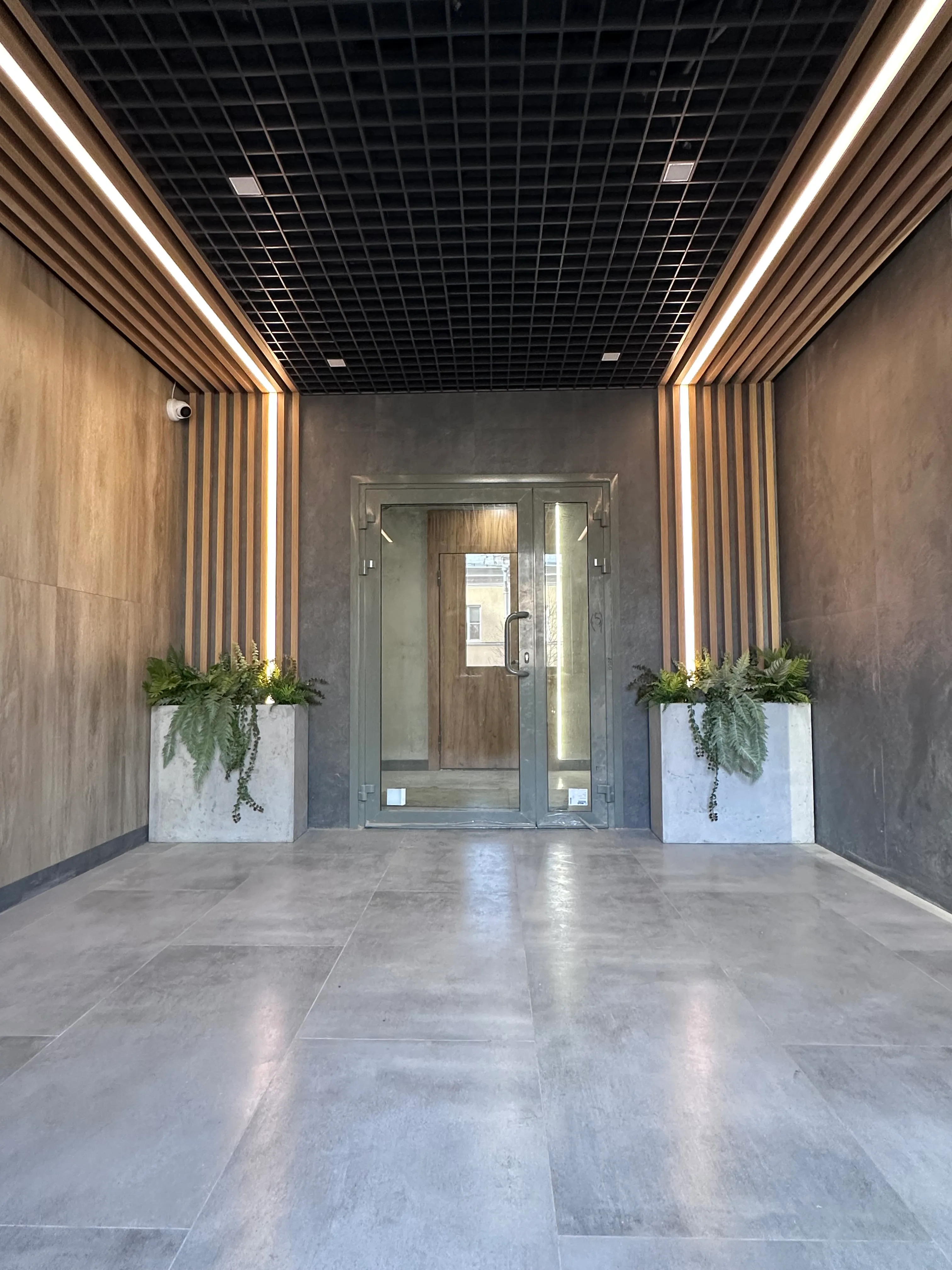 Озеленение парадных в доме искусственными растениями в бетонных кашпо.