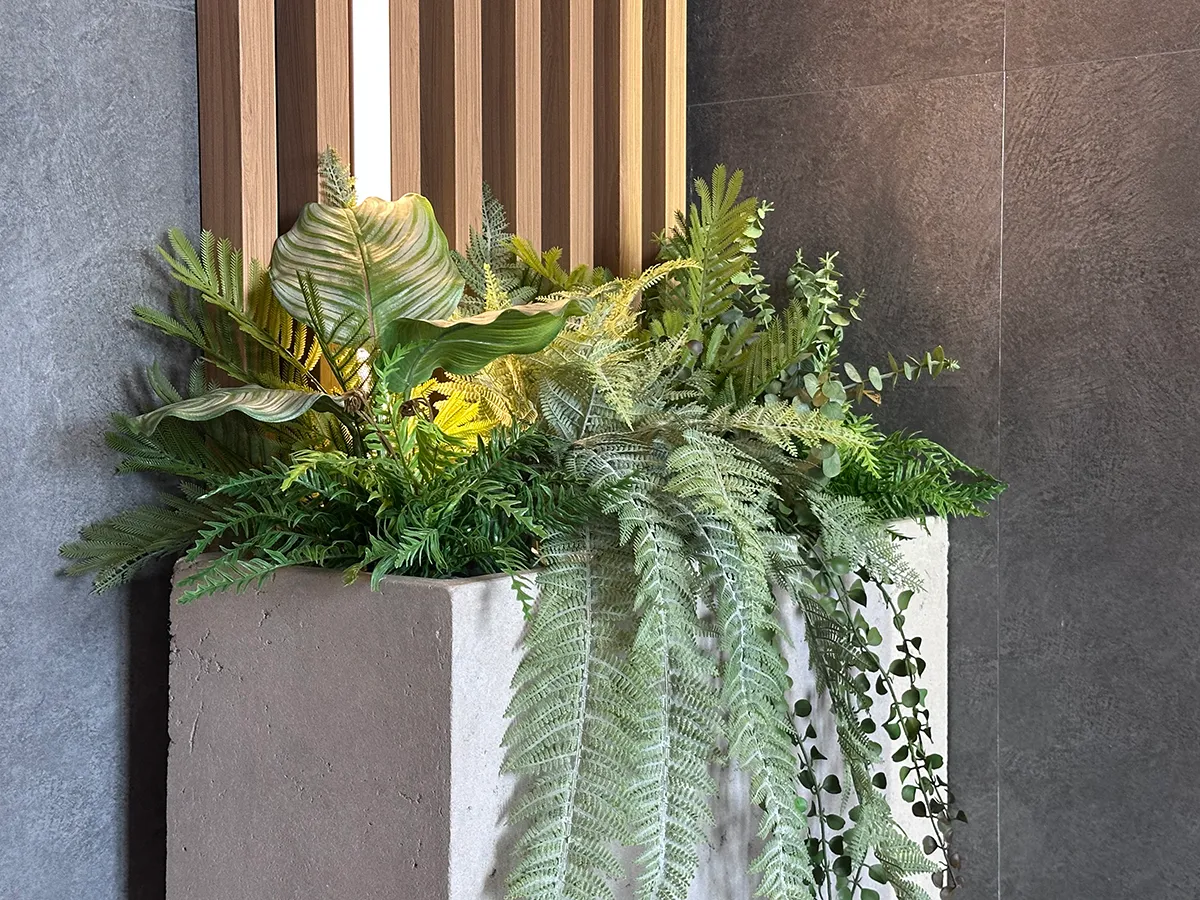 Озеленение парадных в доме искусственными растениями в бетонных кашпо.