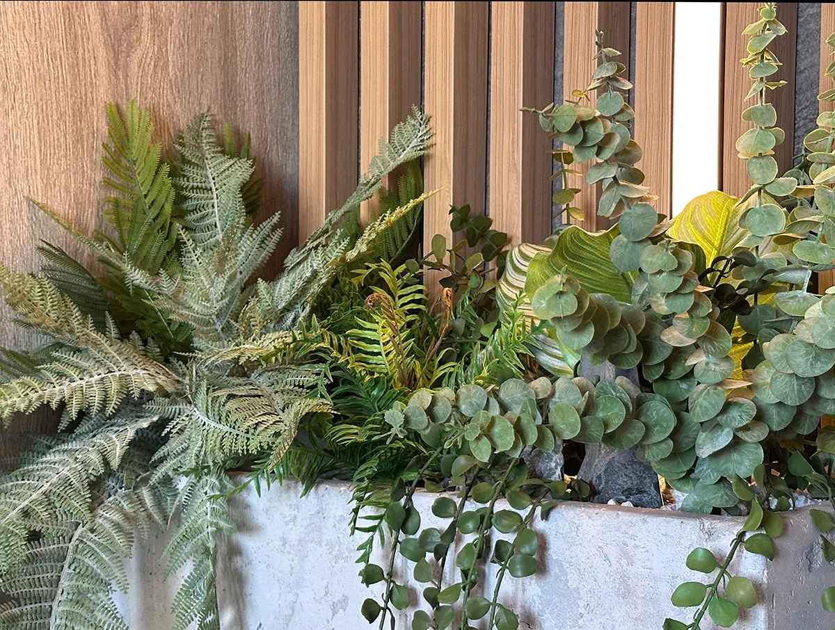 Озеленение парадных в доме искусственными растениями в бетонных кашпо.