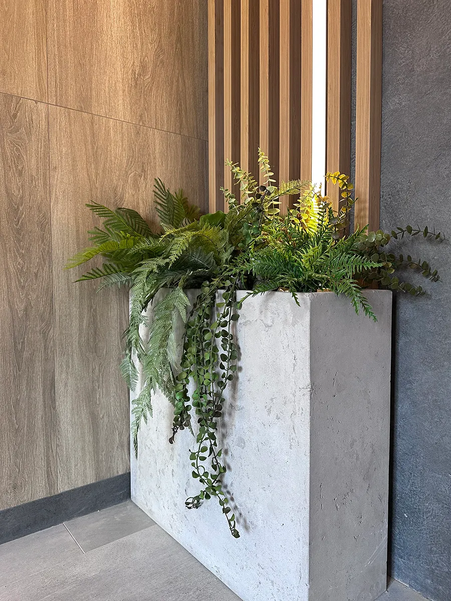 Озеленение парадных в доме искусственными растениями в бетонных кашпо.