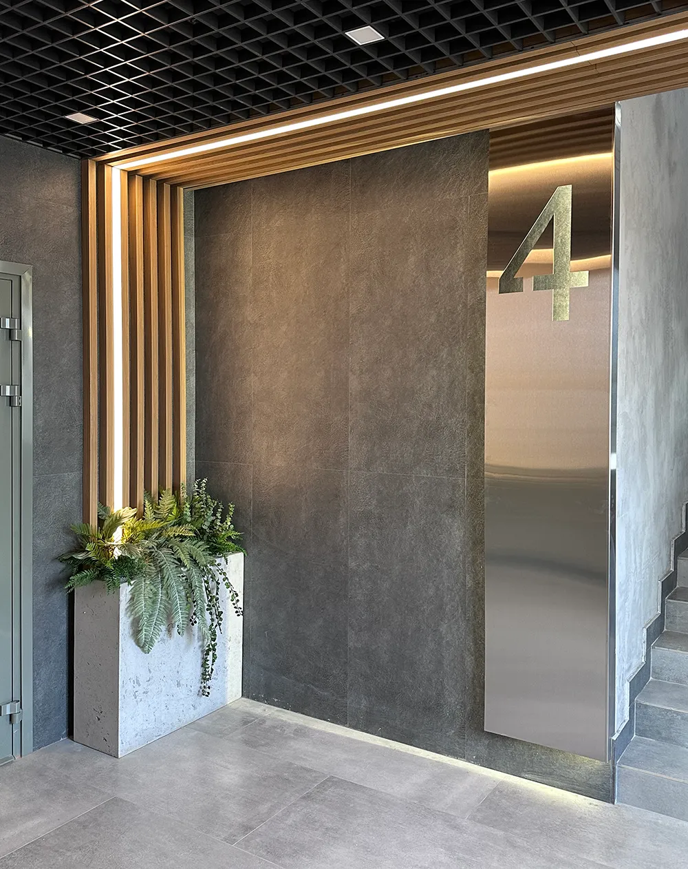 Озеленение парадных в доме искусственными растениями в бетонных кашпо.